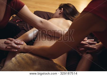 Two Massage Therapist Doing Healing Massage, Massage In Four Hands. Woman Enjoying In Relaxing Massa