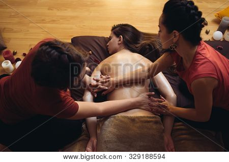 Two Massage Therapist Doing Healing Massage, Massage In Four Hands. Woman Enjoying In Relaxing Massa