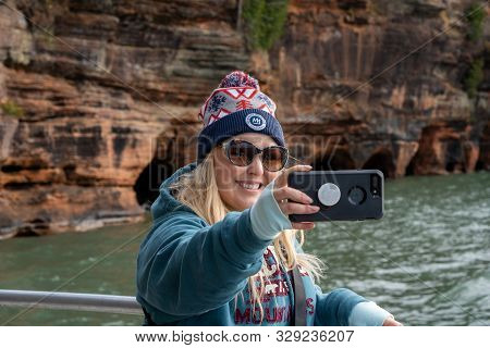 Bayfield, Wisconsin - October 19, 2019: Cute Blond Woman Takes A Selfie With A Smart Phone While On 
