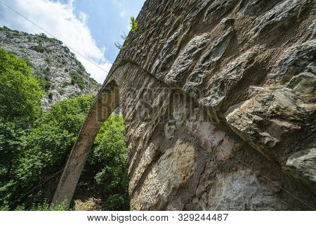 Low Angle Point Of View Of Structure And Arch Of Historic Stone Single Arch Pedestrian Bridge At Zag