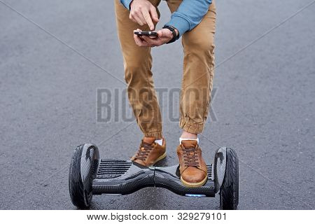Smartphone In Hands With Application For Electrical Gyro Scooter. Man Use Hoverboard Outdoor