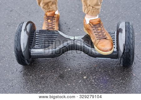 Man Using Hoverboard On Asphalt Road, Close Up. Feet On Electrical Scooter Outdoor