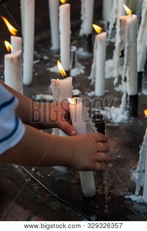 Toddler child with many lit candles holding one of them