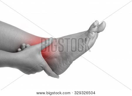 Woman With Ankle Pain Using Hand Holding Leg. Massaging Painful Her On White And Black Background. D