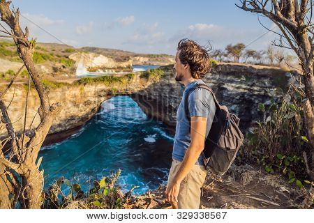 Young Man Tourist Near Broken Beach In Nusa Penida, Indonesia Angels Billabong Beach. Popular Touris