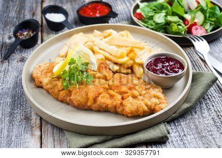 Fried Wiener schnitzel from veal topside with French fries and lettuce as closeup modern design plate 