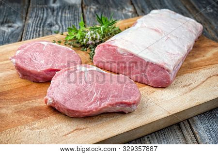 Raw dry aged veal tenderloin with bouquet garni as closeup on wooden cutting board 