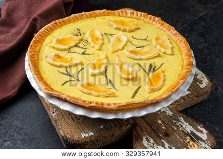 Traditional French Autumn pumpkin tarte offered as closeup in a backing form on an old wooden cutting board 