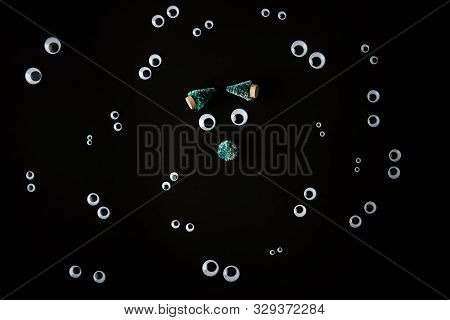Funny Face Made From Jiggly Eyes And Little Fir Tree And Some Pairs Of Googly Eyes Around It On Blac