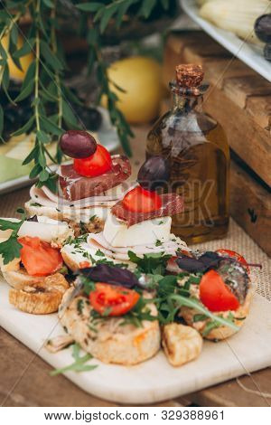 Close Up Of Sandwiches With Cheese And Meat And Other Food And A Bottle Of Olive Oil On The Table.