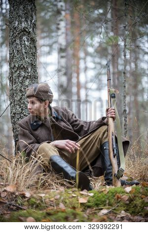 A Soldier Of World War Ii Is Sitting By The Tree With A Cigarette
