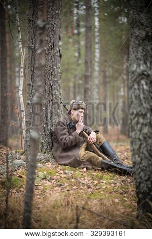 A Soldier Of World War Ii Is Sitting In The Forest And Smoking