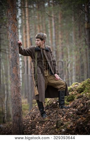 A Soldier Of World War Ii Is Standing Near The Tree And Looking On The Left