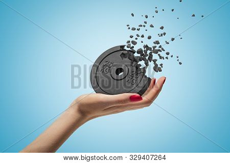 Side Closeup Of Womans Hand Facing Up And Holding Black 25kg Weight Plate That Is Dissolving In Piec