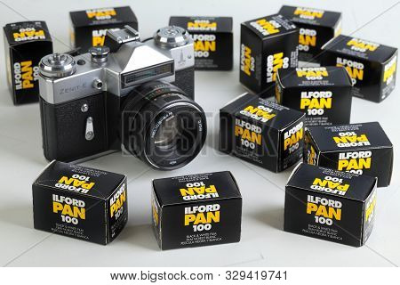 The Old Soviet 35 Mm Slr Film Camera Zenit E, Released 1980, On White Cement Background With Film Pa