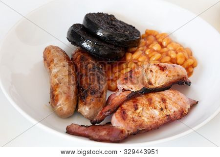 Cumberland Sausages, Back Bacon, Baked Beans And Black Pudding In A White Bowl