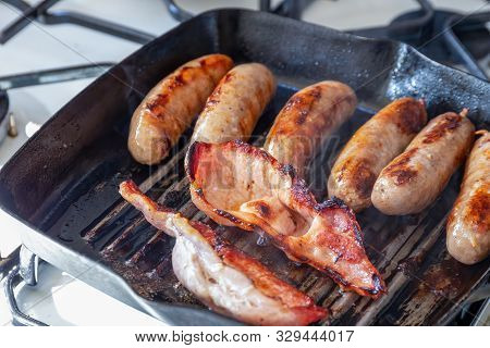 Cumberland Sausages And Back Bacon Cooking In A Griddle Pan