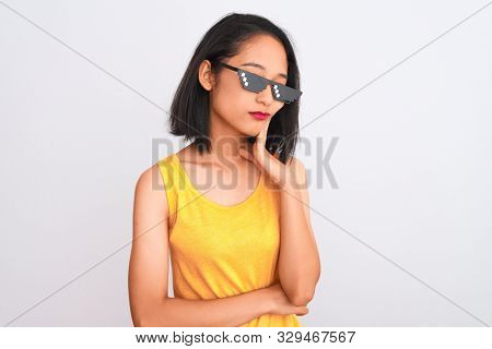Young beautiful chinese woman wearing thug life sunglasses over isolated white background thinking looking tired and bored with depression problems with crossed arms.