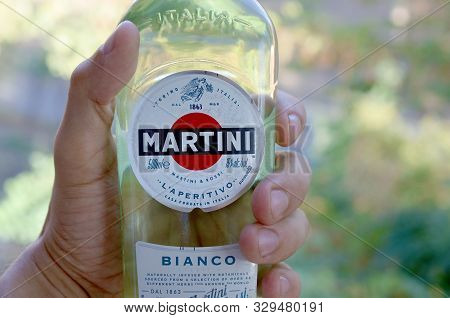Kharkov, Ukraine - September 23, 2019: Bottle Of Vermouth Martini Rossi In Male Hand On A Green Tree