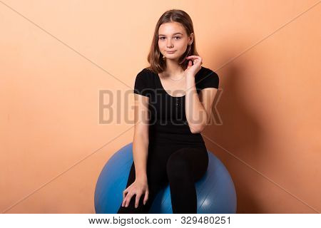 Girl On A Gym Ball, On A Light Orange Background.