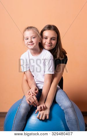 Girls On A Gymnastic Ball, On A Light Orange Background.