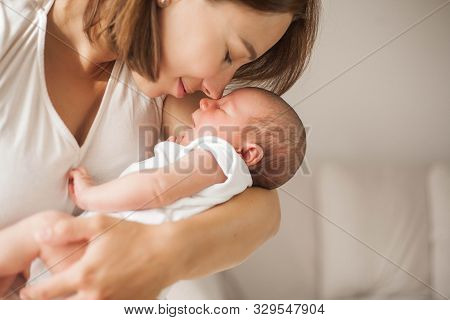 Cute Newborn Baby Sleeping In Mothers Arms. Motherhood.