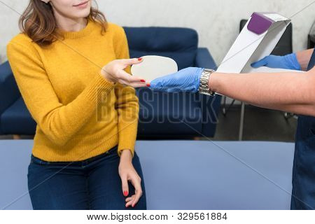 Woman Planning To Have A Breast Implant. Doctor Showing Breasts Implants To Female Patient. Silicone