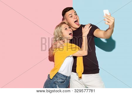 Young Emotional Man And Woman In Bright Casual Clothes Posing On Pink And Blue Background. Concept O