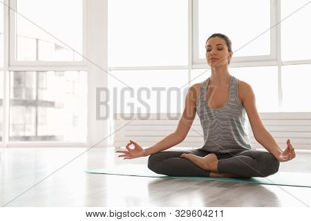 Young Woman Practicing Yoga In Studio. Accomplished Pose (siddhasana)