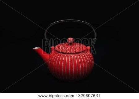 Red Cast-iron Teapot On A Black Background.