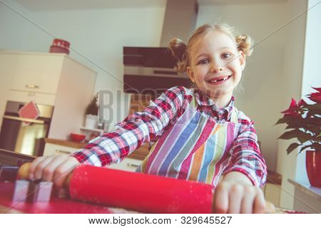 Pretty Little Girl With Funny Pigtails Decoraiting Christmas Cookies Of Different Forms In Kitchen