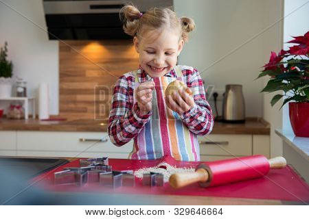 Pretty Little Girl With Funny Pigtails Decoraiting Christmas Cookies Of Different Forms In Kitchen