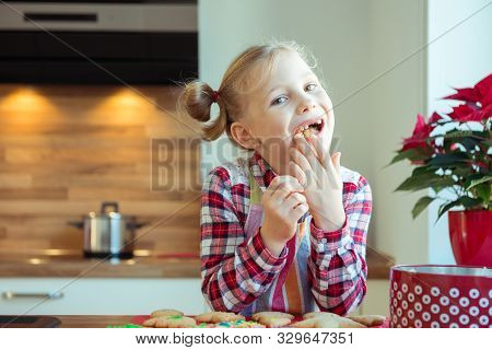 Portrait Of Pretty Little Girl With  Funny Pigtails Decoraiting Christmas Cookies
