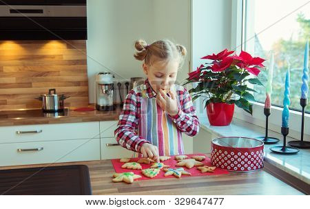 Pretty Little Girl With Funny Pigtails Decoraiting Christmas Cookies Of Different Forms In Kitchen