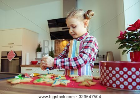 Pretty Little Girl With Funny Pigtails Decoraiting Christmas Cookies Of Different Forms In Modern Ki