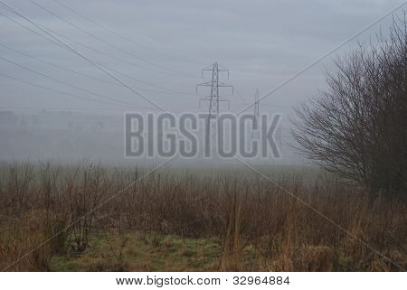 Rząd słupów energii elektrycznej we mgle