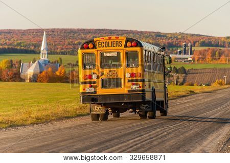 Saint-hermenegilde, Ca - 11 October 2019: Yellow School Bus Driving In The Quebec Countryside At Sun