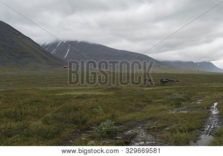 Red Helicopter Supply Hikers At Mountain Lodge Salka Stf Hut. Lapland Mountain Ladscape On Summer Cl