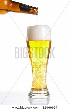 Cerveja derramando do frasco em vidro isolado