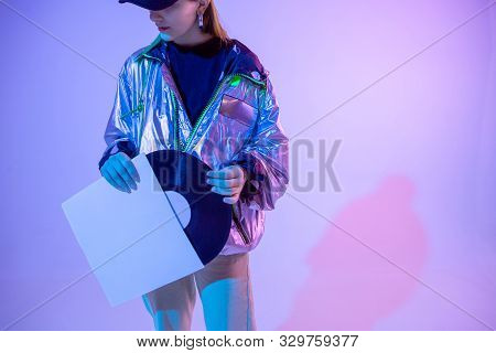 The Girl With The Vinyl Record. Colored Background And Neon Light. Modern Clothes. Music Poster. Ret