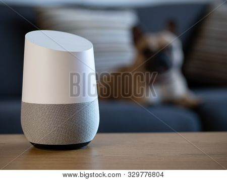Smart Home Voice Activated Speaker In Lounge With Pet Dog In Background