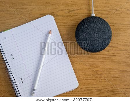 Smart Home Device Speaker On Desk Table With Pencil And Pad Of Paper