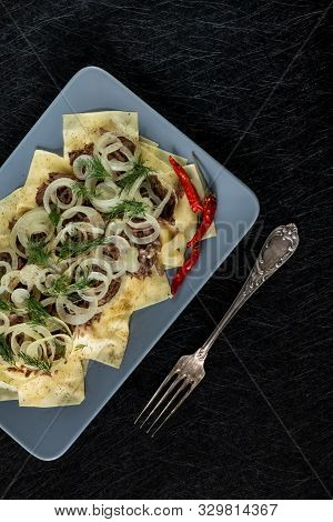 Beshbarmak Is A National Kazakh Dish - Square Pasta With Boiled Meat And Onions. On A Black Backgrou