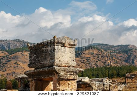 A Large Stone Tomb Against The Backdrop Of Mountains And Sky In A Large Cemetery In Hierapolis.