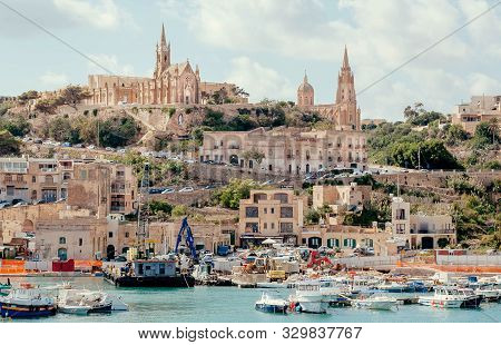 Gozo, Malta: Gozo Island Port View With Fishing Boats And Old Churches On A Hill On 2 October, 2019.