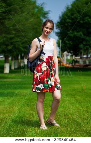 Close up, Young beautiful brunette girl in summer dress walks in the park