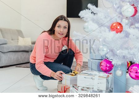 Childish Mother Comes Unnoticed To Christmas Tree At Night, Behaving As If She Wants To Steal A Pres