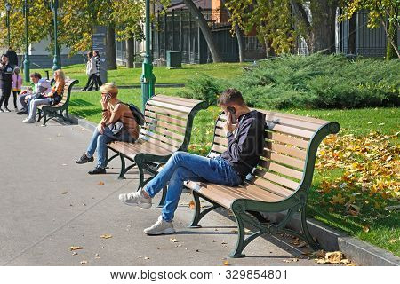 Kharkiv, Ukraine - October 8, 2019: In The Park On A Bench A Guy And A Girl Are Talking On The Phone