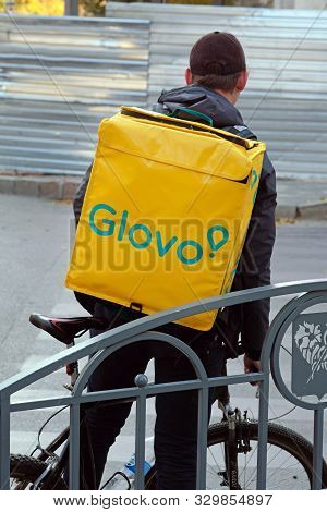 Kharkiv, Ukraine - October 21, 2019: Glovo Delivery Service Employee. Man With A Yellow Backpack And