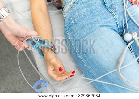 The Doctor Attaches The Electrodes Of The Ecg Pegs To The Patients Wrist.